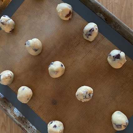 Grab a small amount of dough, about a heaping Tablespoon/golf ball sized amount and roll into a ball (see photo for reference). Set aside on a baking sheet lined with parchment. Repeat with the remaining dough - I usually end up with around 60 cookies depending on how much dough I eat.